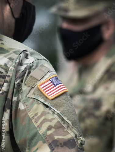 American flag on soldier arm and US soldiers wearing protective face masks. Quarantine in army. Military forces of the United States of America.