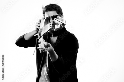 a man with a guitar emotions music game performance leather jacket sunglasses light background