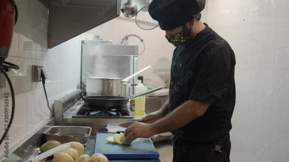 chef cooking with a medical mask and uniform in a restaurant kitchen. Security measures in restaurants due to the coronavirus chef cooking with a medical mask and uniform in a restaurant kitchen. Security measures in restaurants due to the coronavirus