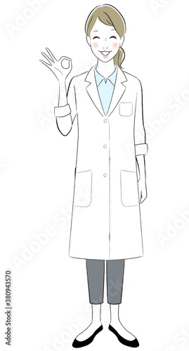 A female doctor wearing lab coat smiling showing ok sign