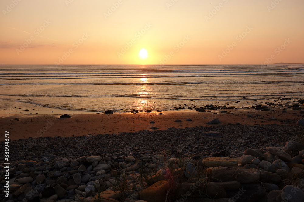 Obraz premium Malerischer romantischer Sonnenuntergang am Meer mit leichtem Wellengang. Treibgut an einem steinigen Strand. sligo strandhill ocean links connacht.