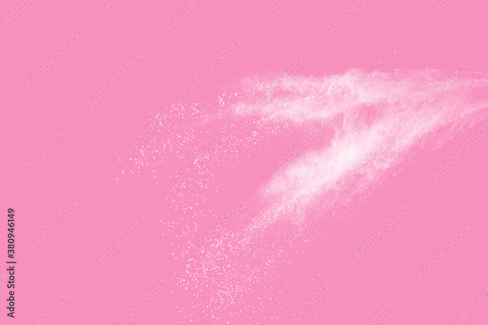 Abstract white powder explosion. Closeup of white dust particle splash isolated on pink background.