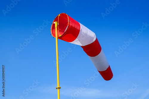a striped meteorological windsock on a background of a blue sky