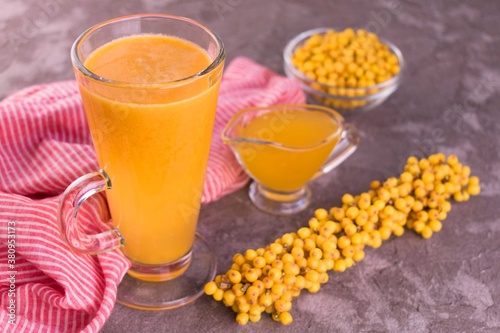 Vitamin juice from sea buckthorn and honey in a glass on a gray background.