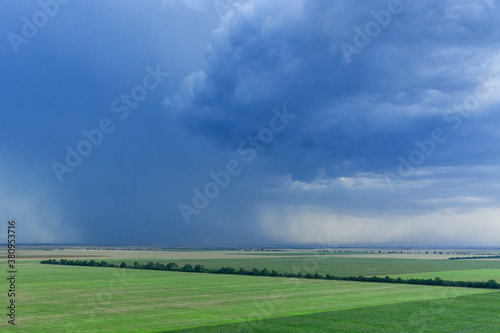 Dark rainy sky and dramatic black clouds being raining. Big rain storm and fields © alexmina