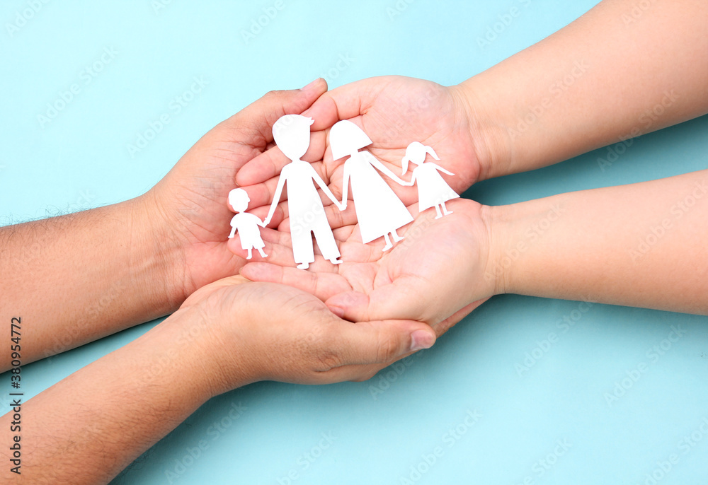 hands holding paper family cutout on blue background. hands holding paper family cutout on blue background.