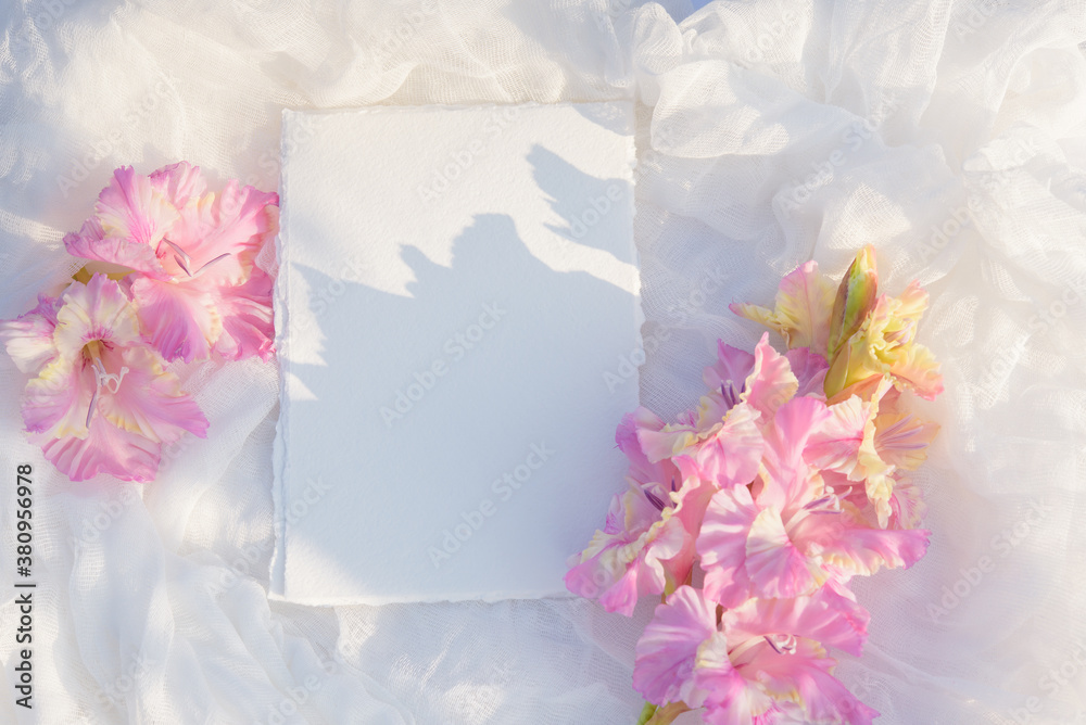 Blank paper card with copy space . Pink gladiolus flower on white textile background. Styled stock photography for display your design, lettering, font, illustration, wedding stationary. Flat lay Blank paper card with copy space . Pink gladiolus flower on white textile background. Styled stock photography for display your design, lettering, font, illustration, wedding stationary. Flat lay