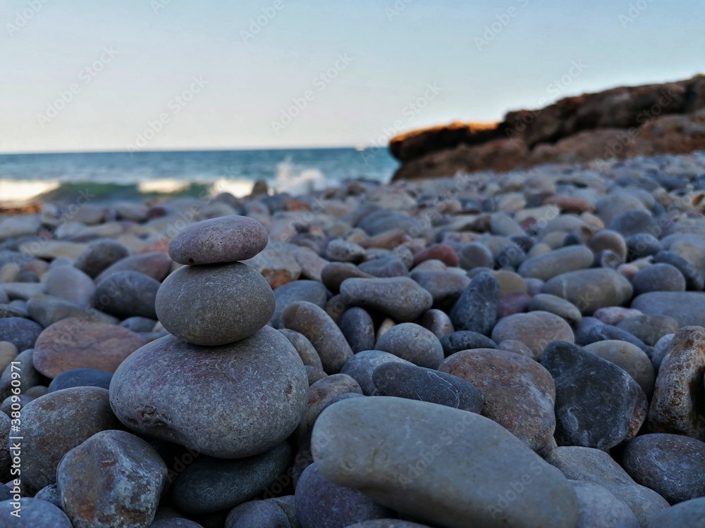 Set of stones on a stone beach with the sea and waves in the background Set of stones on a stone beach with the sea and waves in the background