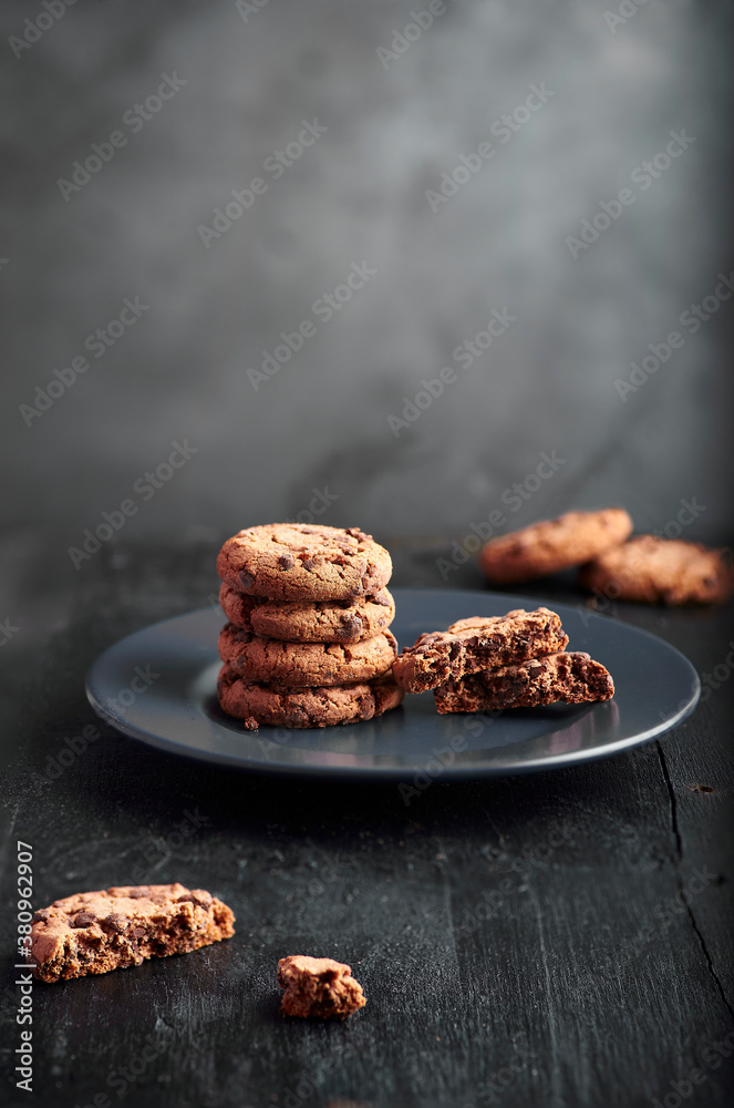 cookies with chocolate shavings on top of a plate on a black background. cookies with chocolate shavings on top of a plate on a black background.