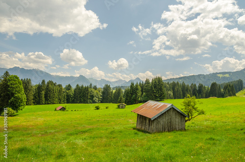 Grüne Bergwiese mit kleinen Holzhütten in Bayern