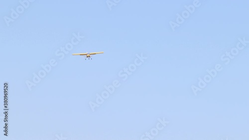 A yellow Tecnam small airplane flying far away in the blue sky photo