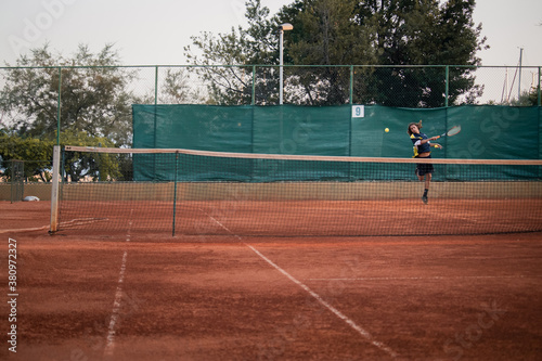 Split Croatia September 2020 Wide shot of a dirt orange tennis field, man on the other side spinning to hit the ball which is flying towards the camera