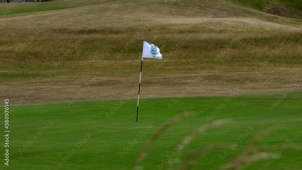 a golf flag waving in the wind filmed in slow motion 4k video. golf uk course Scotland.