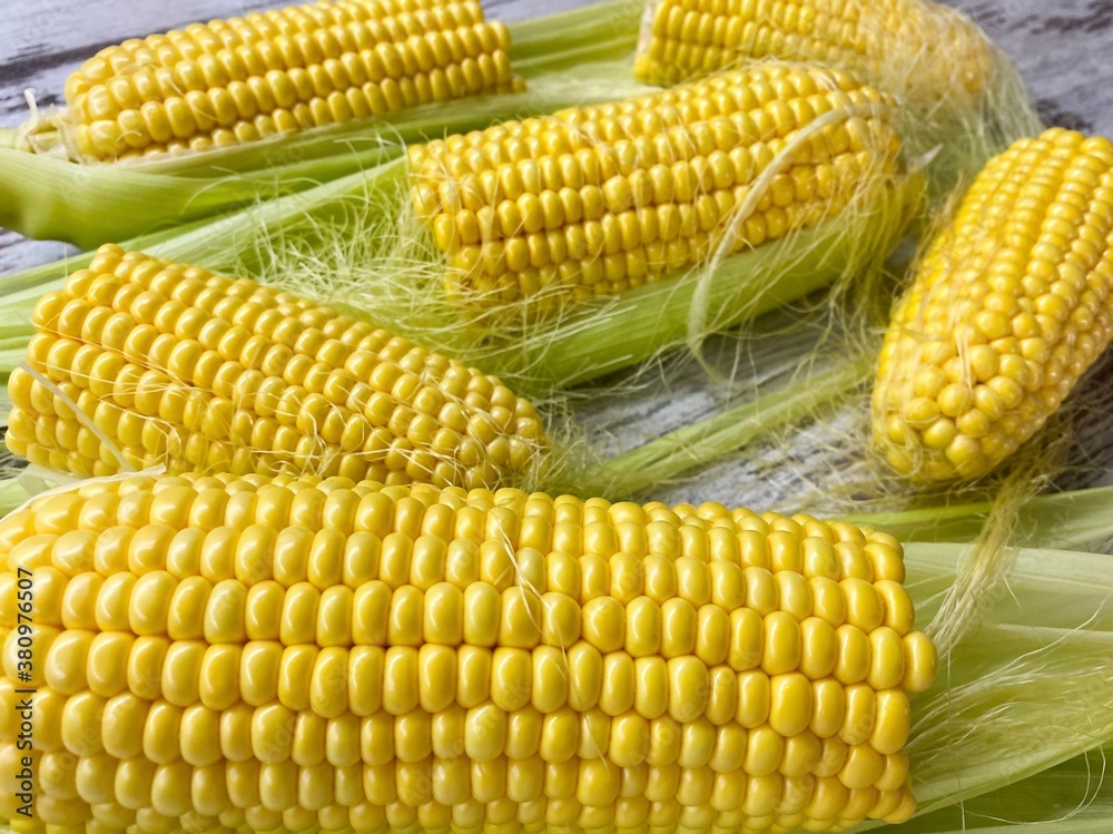 Close-up of ripe raw corn swings on an abstract wooden surface.The concept of proper healthy nutrition, agriculture. Close-up of ripe raw corn swings on an abstract wooden surface.The concept of proper healthy nutrition, agriculture.