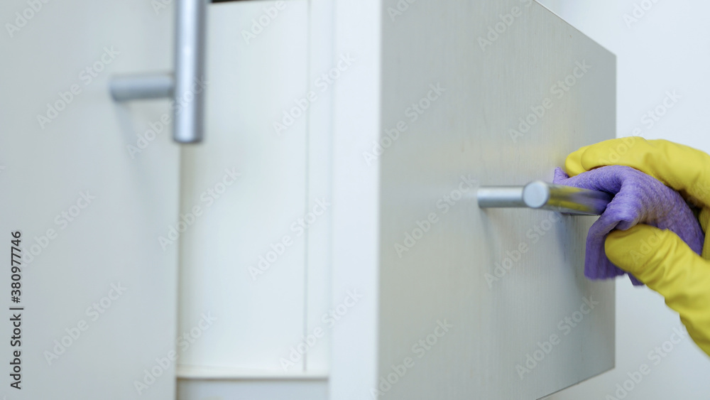 Closeup Image with Person Hands Wearing Protective Yellow Household Gloves Cleaning the Kitchen Furniture Closeup Image with Person Hands Wearing Protective Yellow Household Gloves Cleaning the Kitchen Furniture
