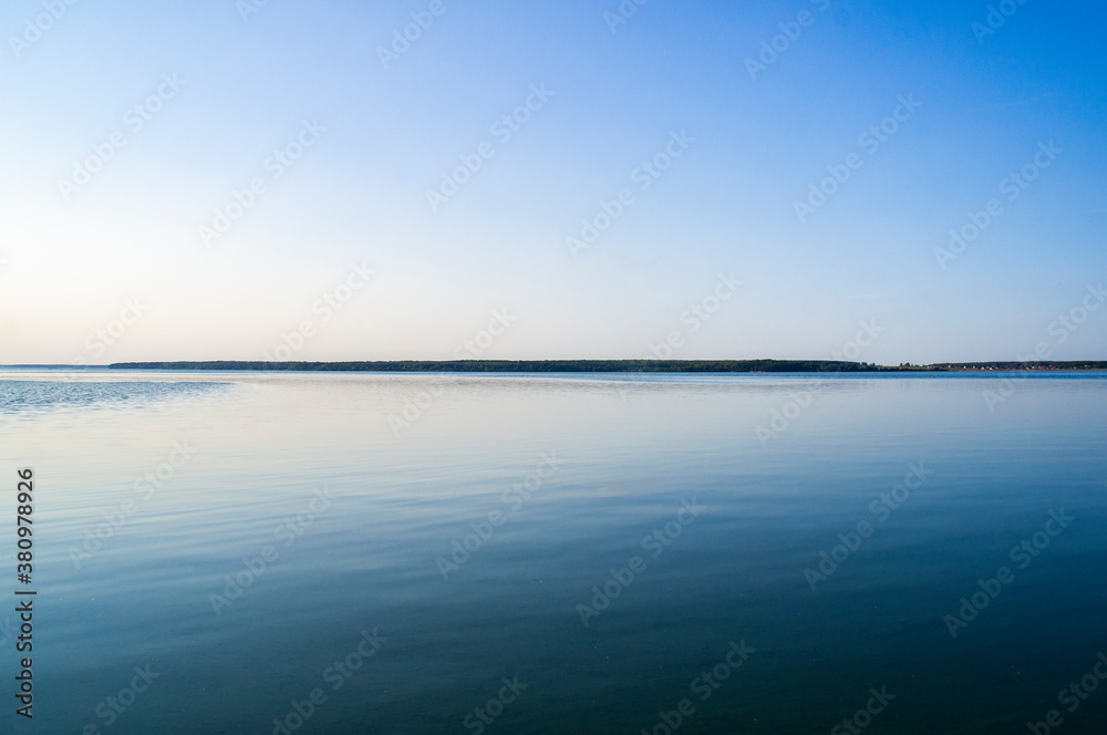 Sunrise over blue big lake with sky reflection in water Sunrise over blue big lake with sky reflection in water