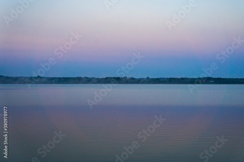 Sunrise over blue big lake with sky reflection in water