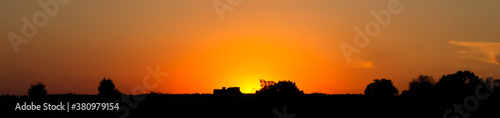 Hot sunset horizon with trees and houses dark contours panoramic background