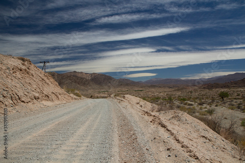 Desert route 40 across the death valley in Salta  Argentina. View of the dirt road  desert and mountains under a beautiful blue sky with clouds.