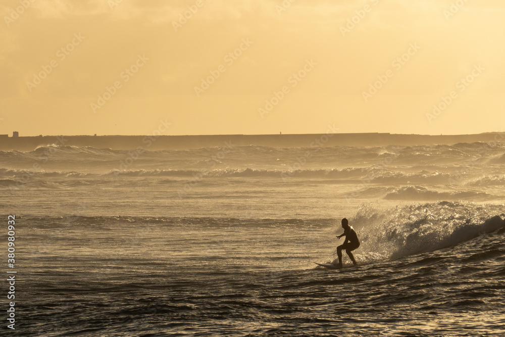 Surfer silhouette riding a wave at sunset