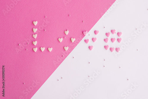 Candies hearts on pink and white paper. Flat lay for Valentine’s Day. Creative sweet concept. Background, top view © Iryna