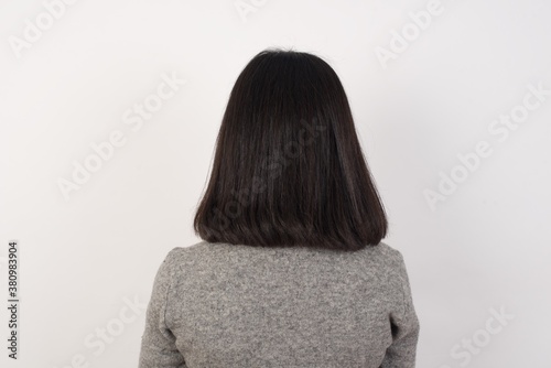 The back view of a Young businesswoman with retro short hairdo wearing casual clothes standing over isolated white background Studio Shoot.