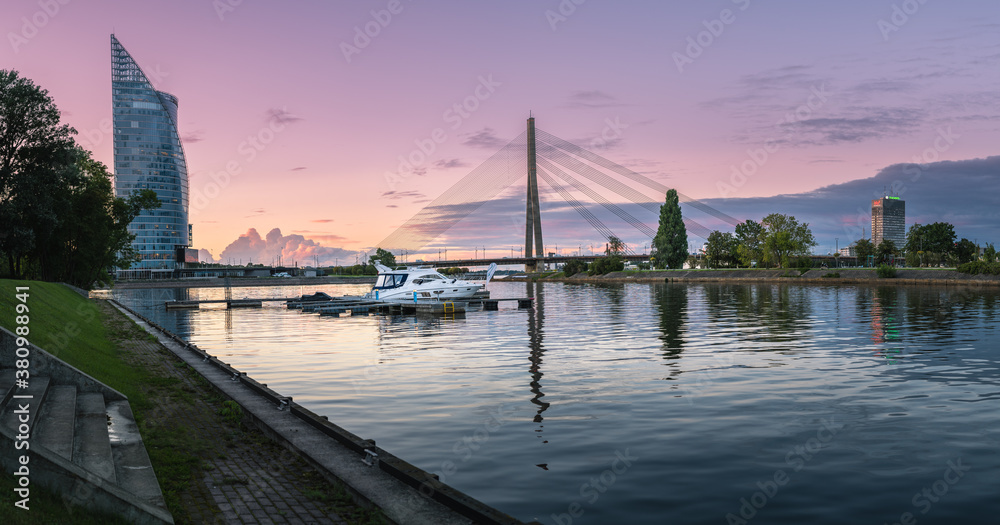 Riga city panorama with colorful sunset in the sky. Modern architecture meets old town. Picturesque view over riverside. 