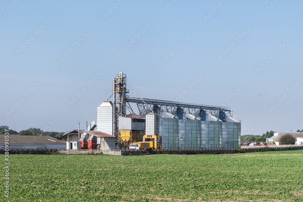 Modern Granary elevator with silver silos on agro-processing and manufacturing plant for processing drying cleaning and storage of agricultural products, flour, cereals and grain. Modern Granary elevator with silver silos on agro-processing and manufacturing plant for processing drying cleaning and storage of agricultural products, flour, cereals and grain.