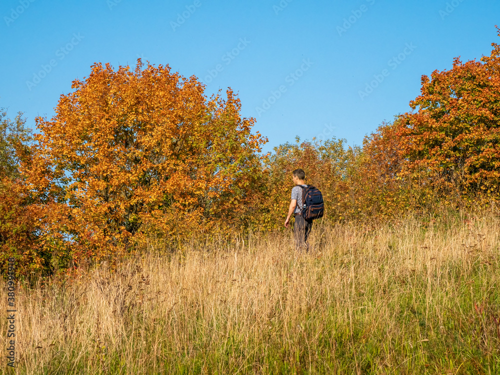 A man with a backpack on a trekking trip in the fall goes down the hill. A man with a backpack on a trekking trip in the fall goes down the hill.