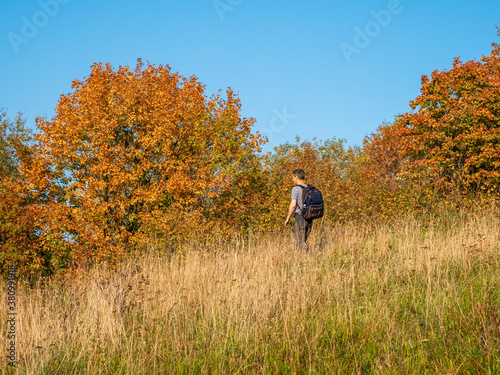 A man with a backpack on a trekking trip in the fall goes down the hill.