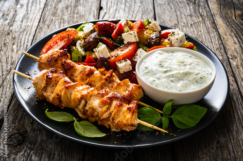 Fried souvlaki, greek salad and tzatziki on wooden table photo