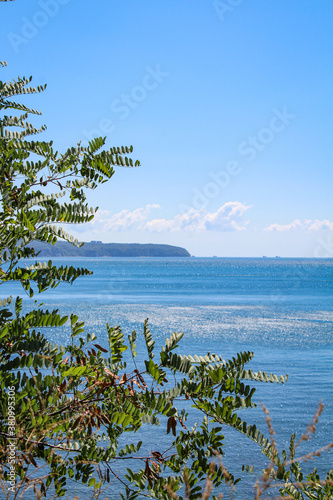 Fototapeta Naklejka Na Ścianę i Meble -  The shore juts out into the blue sea. Calm seascape
