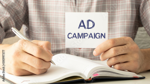 Closeup on businessman holding a card with text Ad Campaign, business concept image with soft focus background and vintage tone