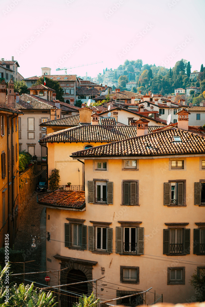 Close up. The street view of the old Italian colorful buildings with wooden shutters, tiled roofs, towers, shops in the city center of Bergamo, Lombardy, Italy. Vintage European architecture. Close up. The street view of the old Italian colorful buildings with wooden shutters, tiled roofs, towers, shops in the city center of Bergamo, Lombardy, Italy. Vintage European architecture.