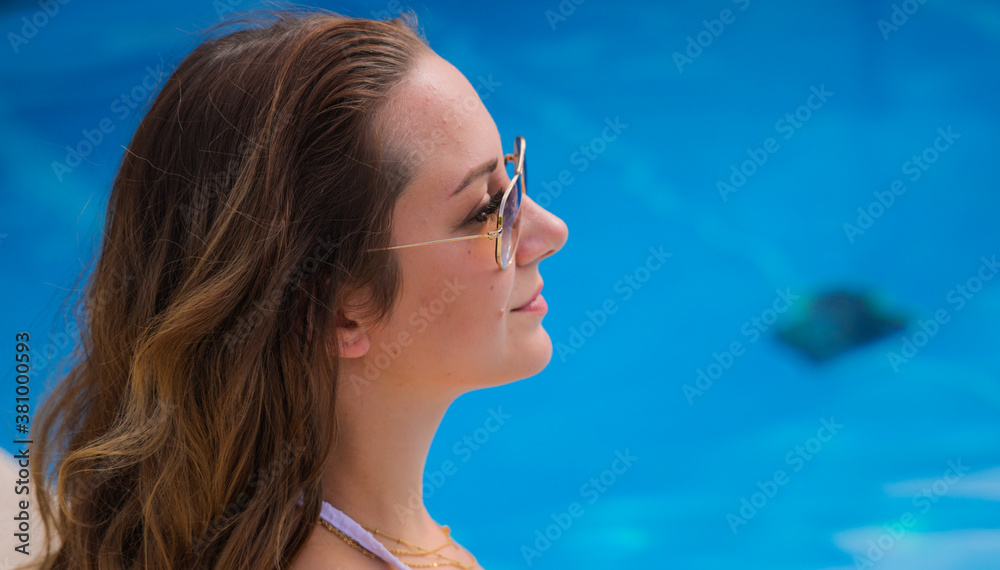 Sexy woman relaxes by a swimming pool on a sunny day