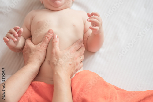 Massage stomach for little child infant makes a doctor massage therapist in a massage room with oil on bed. massage with colic tummy. manual therapy for childrens heals. motherhood. photo