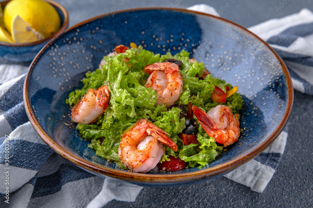 A light, nutritious salad of shrimp, lettuce and olives. Natural delicious food. Greek cuisine menu. Still life in a marine style on a blue background. A light, nutritious salad of shrimp, lettuce and olives. Natural delicious food. Greek cuisine menu. Still life in a marine style on a blue background.