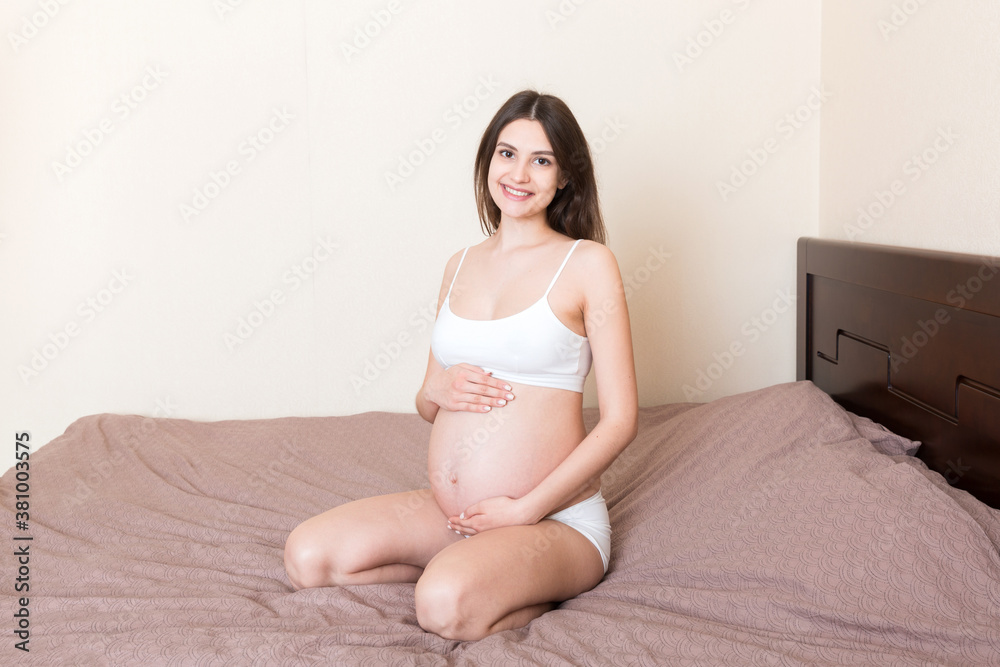 pregnant woman sitting in bed and touching her belly at home. pregnancy expectation concept pregnant woman sitting in bed and touching her belly at home. pregnancy expectation concept