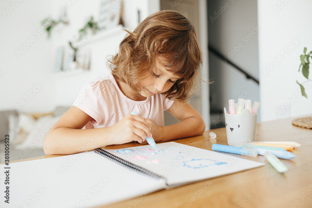 Cute happy little girl, adorable preschooler, 5 years child painting at the table in a white living room at home. Cute happy little girl, adorable preschooler, 5 years child painting at the table in a white living room at home.