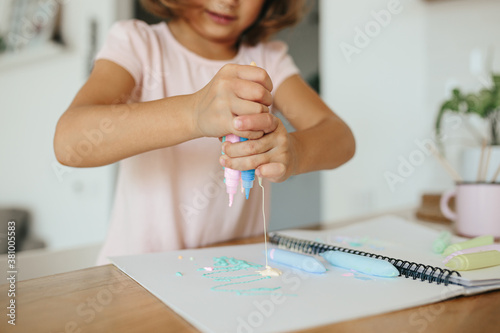 Cute happy little girl, adorable preschooler, 5 years child painting at the table in a white living room at home.
