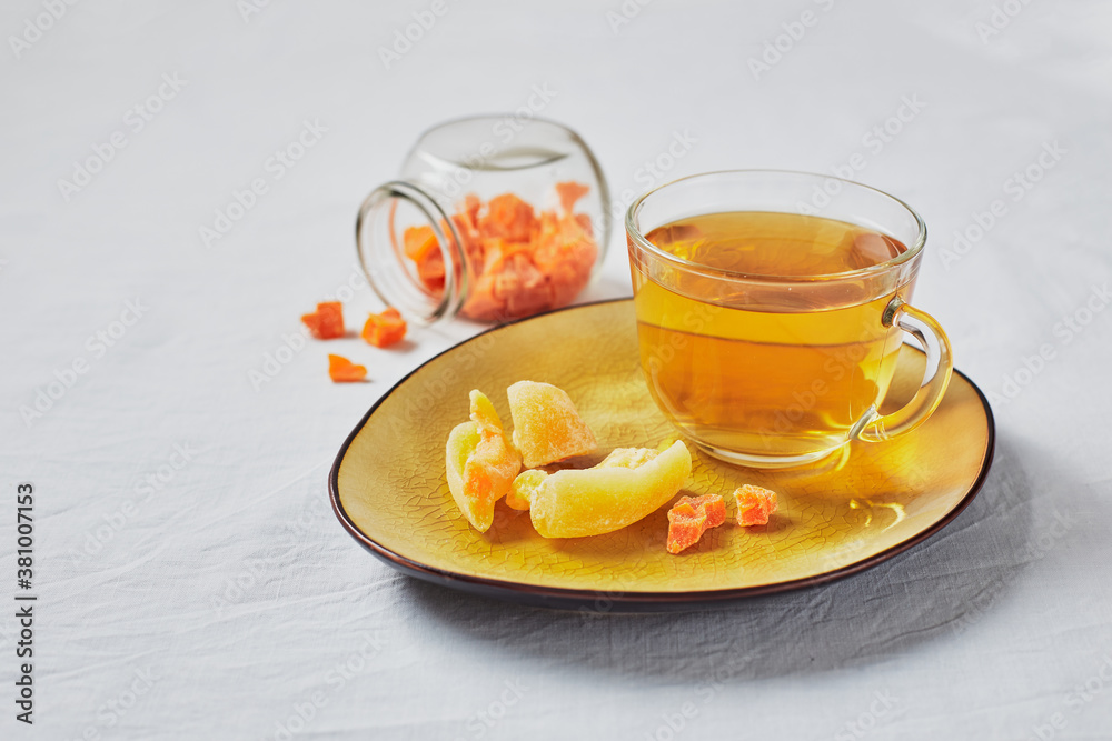 Delicious black tea in glass cup and candied fruits on yellow saucer Delicious black tea in glass cup and candied fruits on yellow saucer
