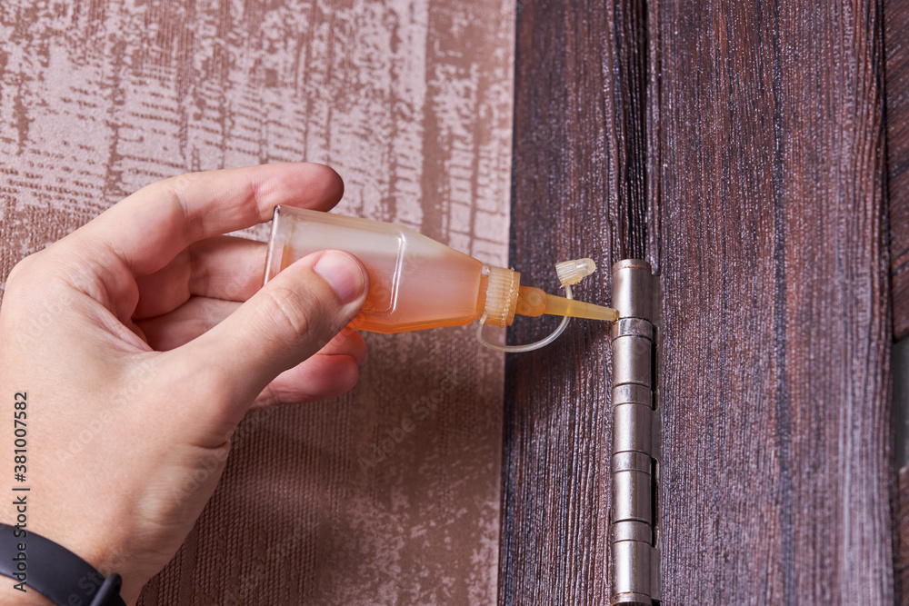 Foto de adjusting door hinge using lubricating oil. indoors. fixing