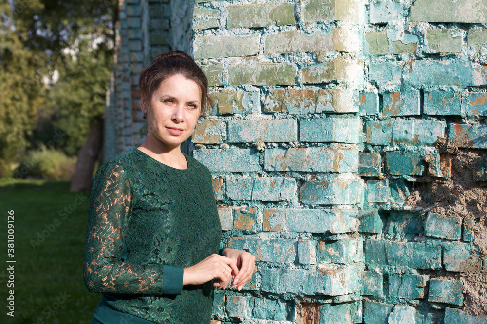Portrait of a girl in a green tracksuit. Against the background of a brick wall.