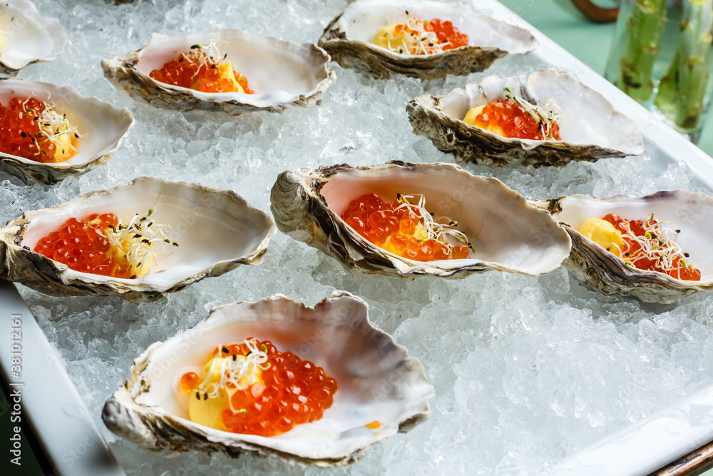 Fresh Oysters close-up on blue plate, served table with oysters, lemon and ice. Healthy sea food. Oyster dinner with champagne in restaurant. Gourmet food. Fresh Oysters close-up on blue plate, served table with oysters, lemon and ice. Healthy sea food. Oyster dinner with champagne in restaurant. Gourmet food.