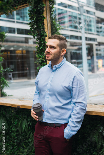 Photo of a young and attractive business man wearing smart casual clothes enjoying a cup of coffee while having a job break. Entrepeneur style.