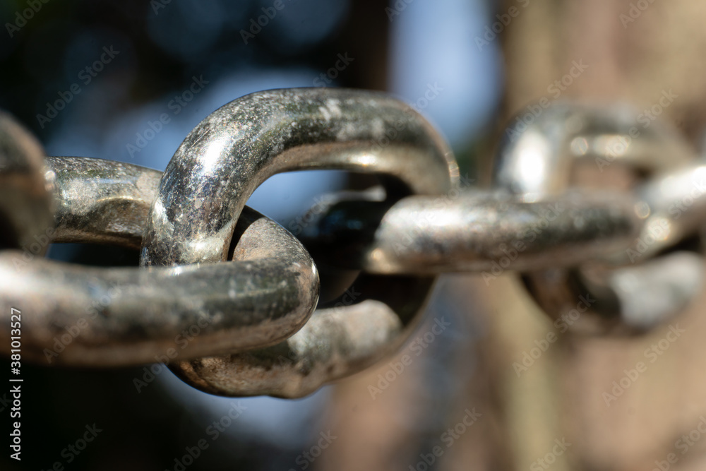 Close-up of the links of a metal chain in sunlight; selective focus; strength and connection; bond Close-up of the links of a metal chain in sunlight; selective focus; strength and connection; bond