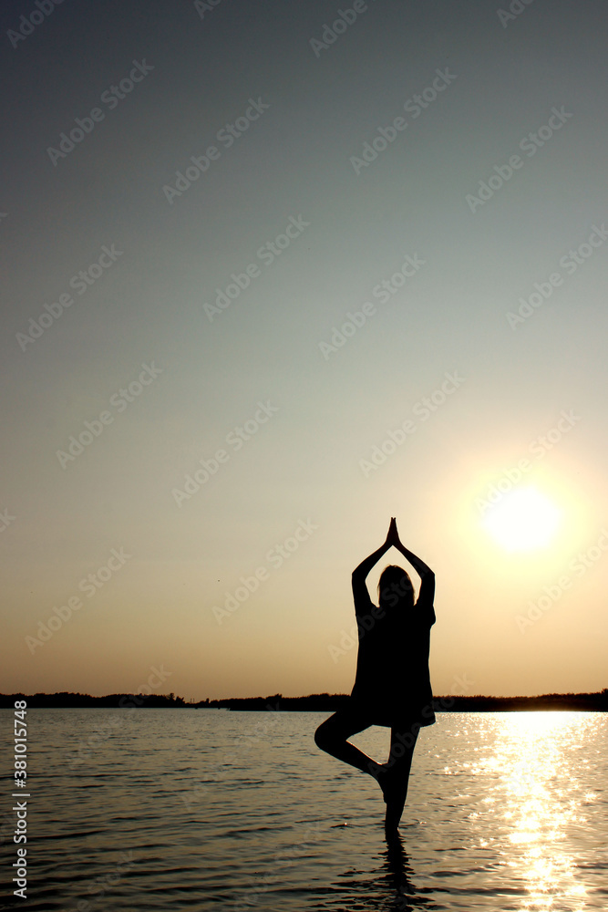 Silhouette of Teenage Girl In A Balancing Yoga Position. Young Girl In Tree Pose Position, Outdoors.