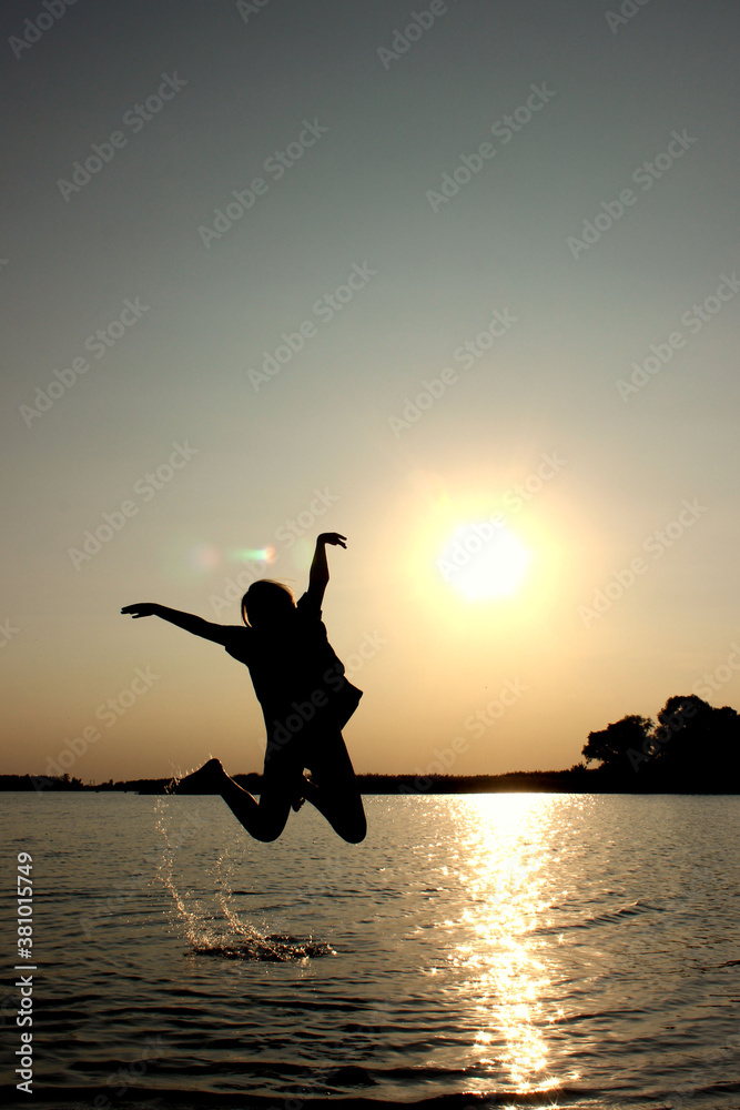 Fototapeta premium Teenage girl jumping outdoors, sunset background. People, travel, nature concept.