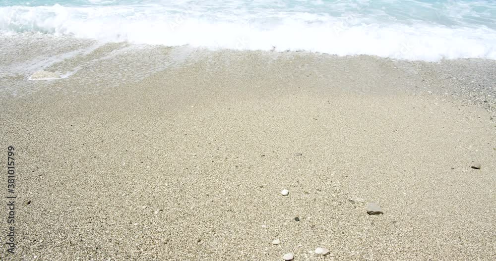 Close up of foaming waves and splashes on sandy beach sunshine. Concept of wild natural relaxation. Close up of foaming waves and splashes on sandy beach sunshine. Concept of wild natural relaxation.