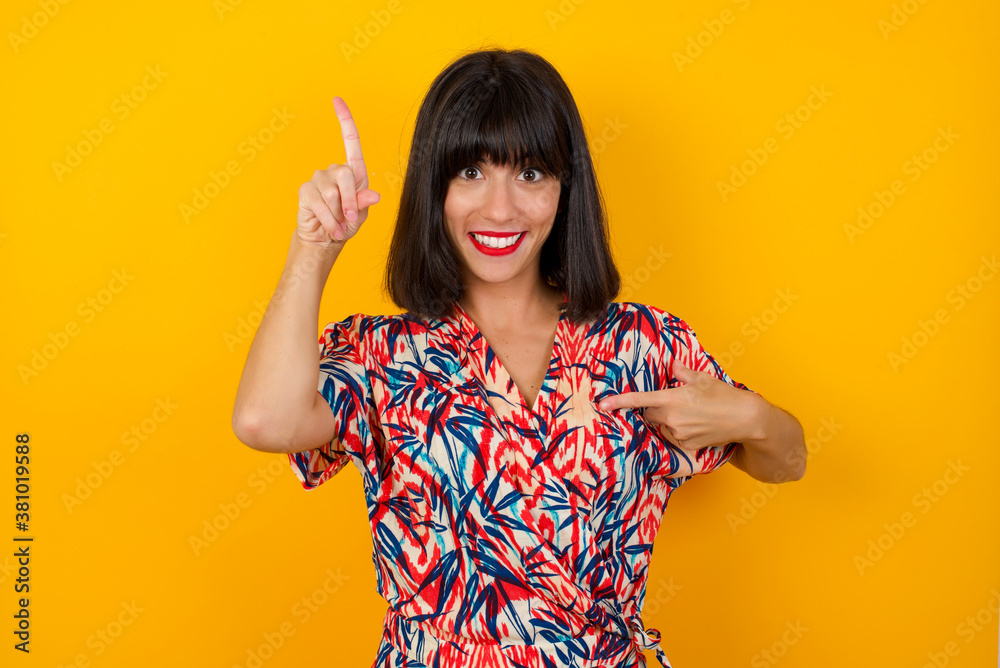Positive glad female says: wow how exciting it is, has amazed expression, indicates something. One hand on her chest and pointing with other hand. Positive glad female says: wow how exciting it is, has amazed expression, indicates something. One hand on her chest and pointing with other hand.